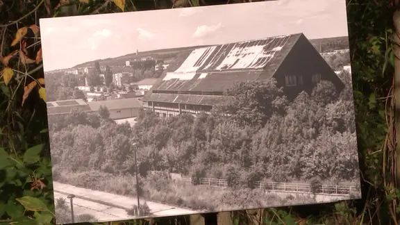 Ein Schwarz-Weiß-Foto der historischen Viehauktionshalle in Weimar auf einem Stativ im Grünen.
