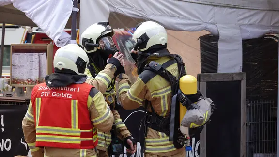 Zwei Feuerwehrleute der Feuerwehr Dresden legen sich Atemschutzmasken an.
