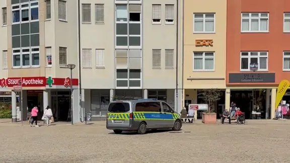 Auf dem Fischmarkt in Halberstadt steht vor Gebäuden ein Polizeiauto.