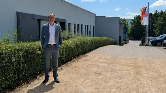ULT-Co-Geschäftsführer Alexander Jakschick in einem grauen Anzug und weißem Hemd vor der Firmenzentrale in Löbau in der sächsischen Oberlausitz