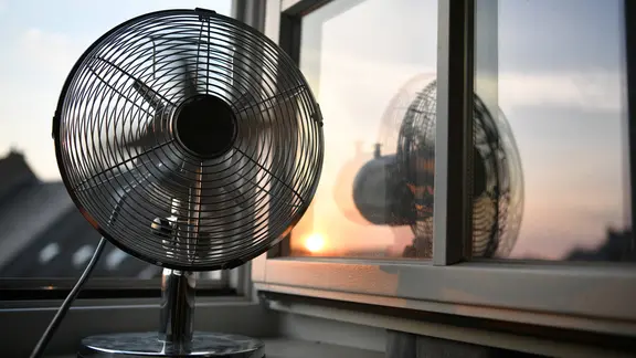 Ventilator steht morgens am offenen Fenster einer Dachwohnung