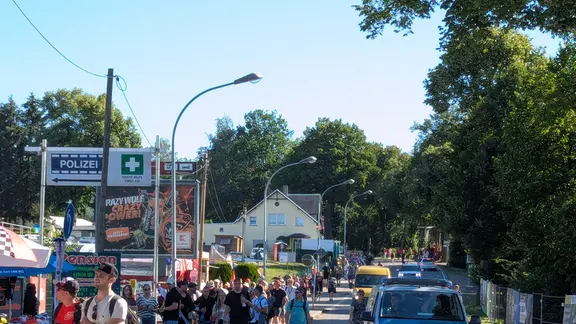 Mehrere große Gruppen Menschen laufen am Straßenrand entlang