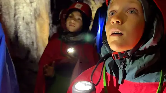 Kinder mit Taschenlampen und Helm in Bergwerksstollen