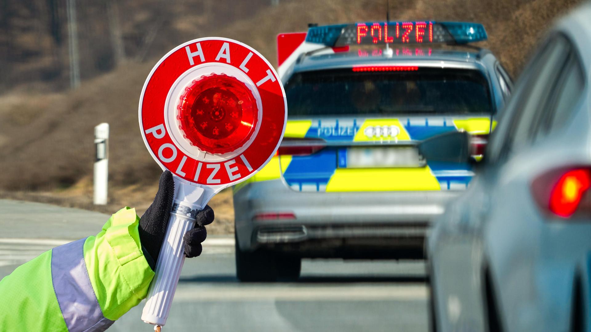 Eine Hand hält eine rote Polizeikelle vor einem Auto.  | picture alliance / CHROMORANGE | Michael Bihlmayer