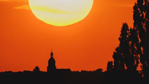 Eine Kirche zeichnet sich ab vor der untergehenden Sonne in Malschwitz.