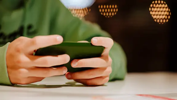 Ein Junge spielt ein Spiel auf seinem Smartphone. 