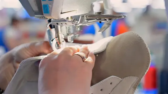 Frau näht Schuh mit einer Nähmaschine