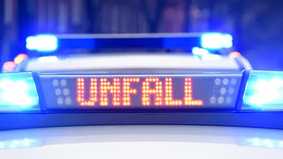 Blaulicht und der Schriftzug "Unfall" leuchtet auf dem Dach von zwei Streifenwagen der Polizei.