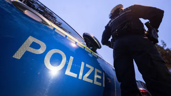 Eine Polizistin steht neben einem Polizeifahrzeug. 