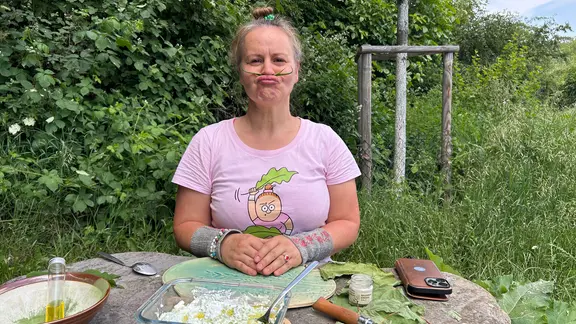Survival Siglinde vor einem Tisch mit zubereiteten Speisen