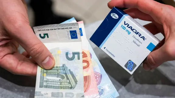 Ein Mann bezahlt Viagra-Tabletten in einer Apotheke. 