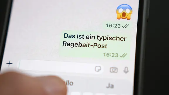 Das Wort Ragebait auf dem Display eines Smartphones in einem Chatverlauf, Juli 2026.
