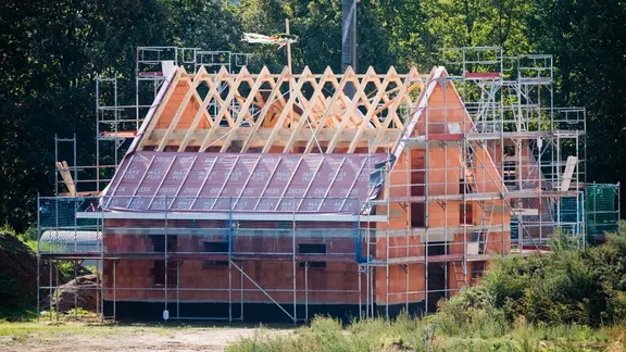 Ein Richtkranz weht am Dachstuhl eines neu gebauten Einfamilienhauses