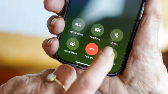 ein smartphone wird von zwei alten Händen gehalten