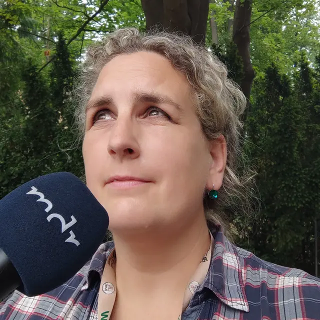 Eine Frau mit Zopf steht vor einem Baum, seitlich im Bild ist ein mdr-Mikro zu sehen