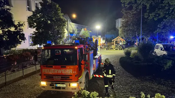 Ein Feuerwehrauto und Feuerwehrkräfte vor einem Gebäude