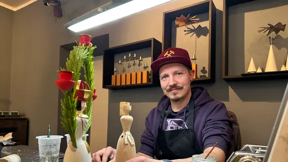 Ein junger Mann bearbeitet eine Holzfigur.