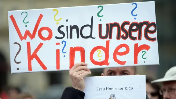 At a rally for the victims of forced adoptions in East Germany, a man holds up a poster with the inscription "Where are our children?" in front of the Brandenburg Gate in Berlin on April 18, 2014.