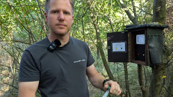 Roy Jacubasch hält ein Röhrchen mit einem Logbuch in den Händen. 