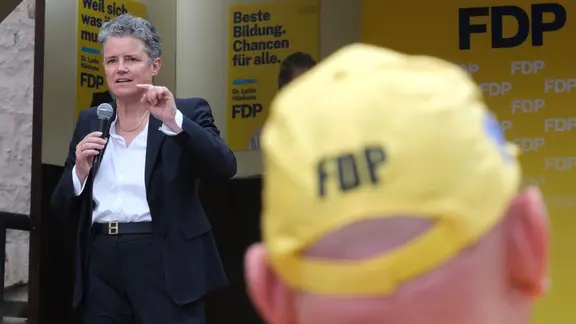 Eine Frau steht auf einer Bühne und spricht in ein Mikrofon.