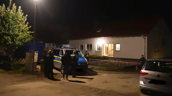 Polizeiauto und Polizisten vor einem abgesperrten Einfamilienhaus in der Nacht.