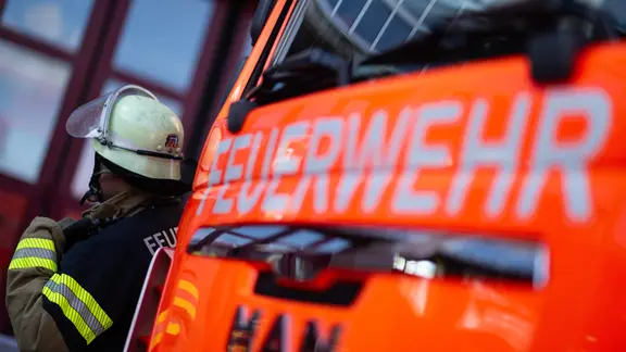 Ein Feuerwehrmann steht neben einem Einsatzfahrzeug der Feuerwehr
