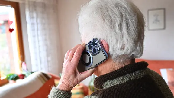 Eine alte Frau hält ein Telefon