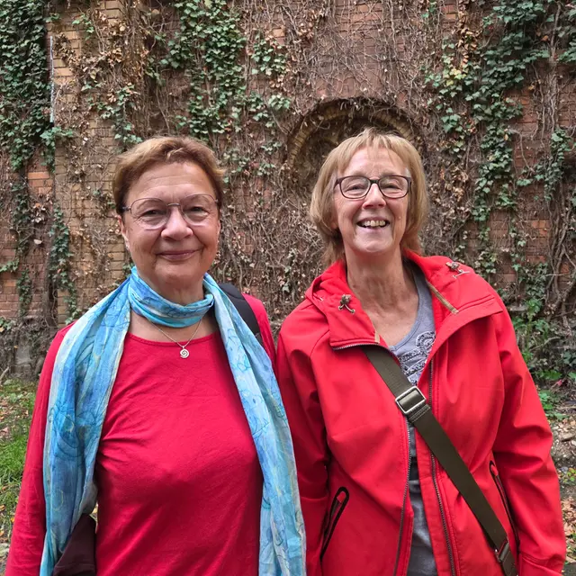 Zwei Frauen in roter Kleidung lächeln in die Kamera.