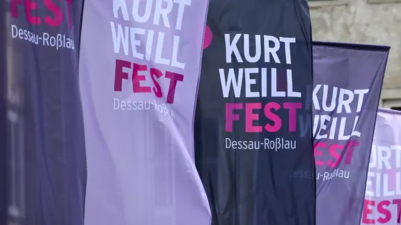 Fahnen in pink mit der Aufschrift "Kurt Weill Fest". 