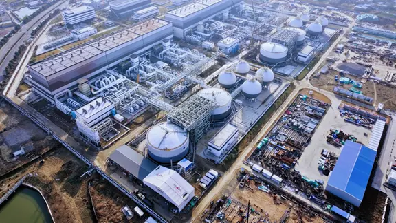 Luftaufnahme einer großen Industrieanlage mit meheren Hallen, vielen Rohrleitungen und Speicherbehältern.