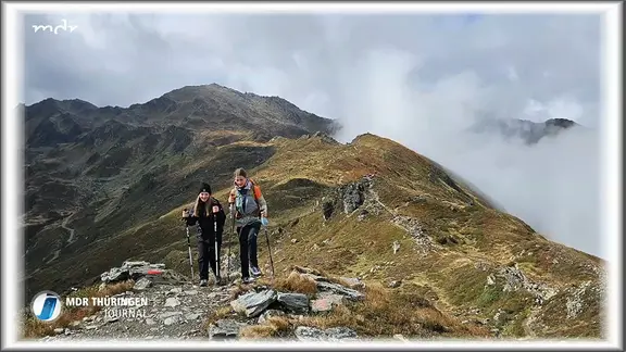 Zwei Schülerinnen wandern auf einem Grat in den Alpen.
