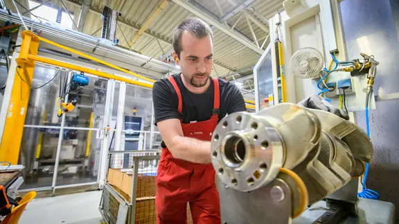 Ein Mann arbeitet in einem Werk an Kurbelwellen.