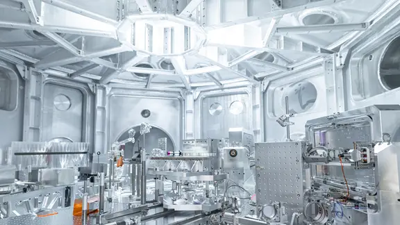 Heller Reinraum mit komplexen Metallapparaturen und optischen Bauteilen für wissenschaftliche Experimente.