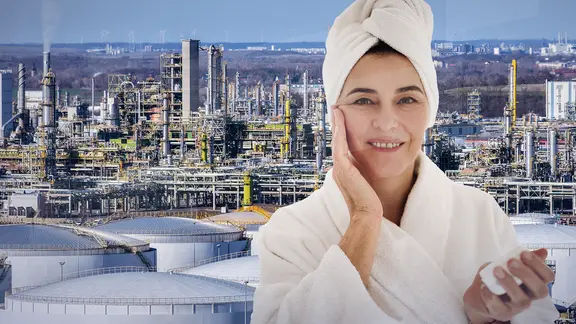 Eine Frau, die sich das Gesicht cremt vor einer Chemieanlage