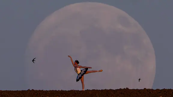 Die Ballerina Deniz Doga Usta tanzt am Abend des 9. Juli 2025 bei Vollmondaufgang hinter den Bergen in der türkischen Hauptstadt Ankara. 