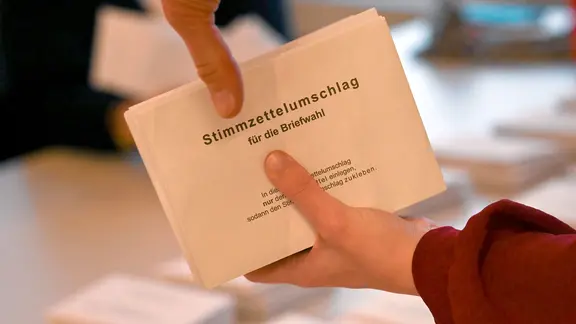 Zwei Hände halten einen Stapel mit Wahlumschlägen