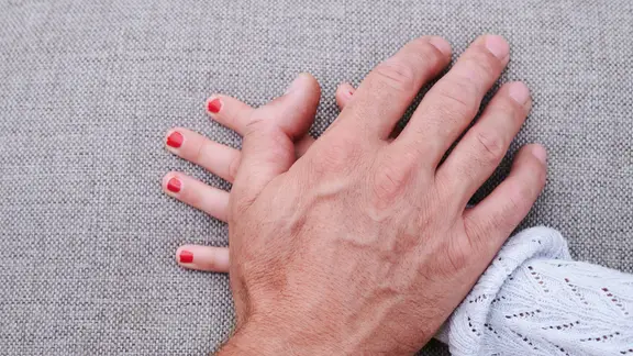 Eine Männerhand liegt auf einer Mädchenhand