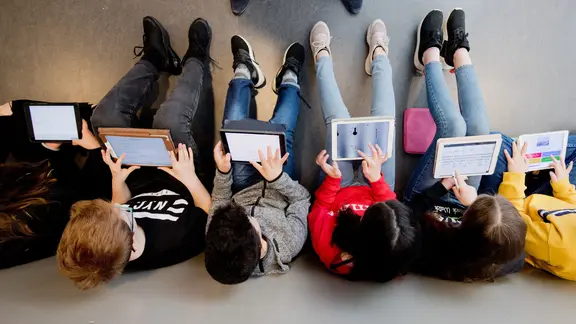 Mehrere Schüler sitzen auf dem Boden und lernen 