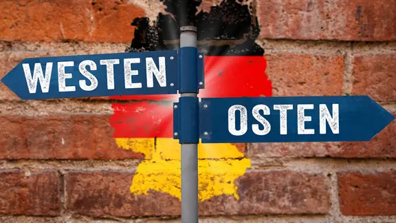 Mauer mit Wegweiser Ost und West