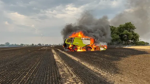 Ein Mähdrescher steht auf einem Feld in Flammen.