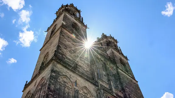 Zwischen den Türmen des Magdeburger Doms scheint die Sonne hindurch.