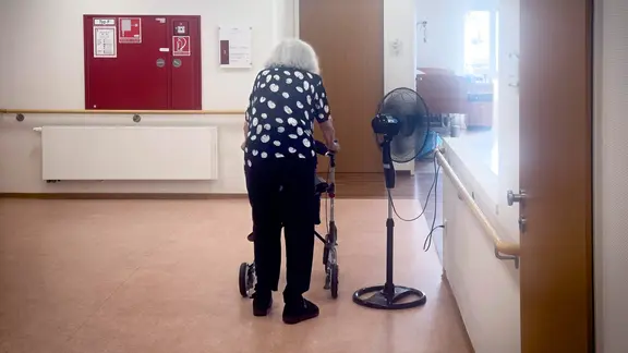 Alte und behinderte Frau mit Rollator in einem Flur von einem Altersheim