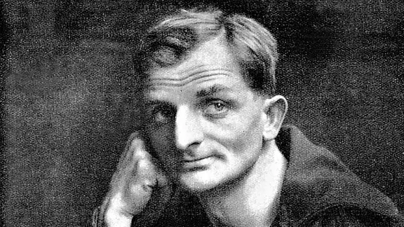 Die Abbildung zeigt ein Porträt des deutschen Schriftstelleres Joachim Ringelnatz, eigentlicher Name Hans Bötticher (1883-1934) in Gedanken versunken am Tisch sitzend mit Gläschen in der Hand.