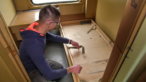 Ein Mann repariert ein Zugabteil