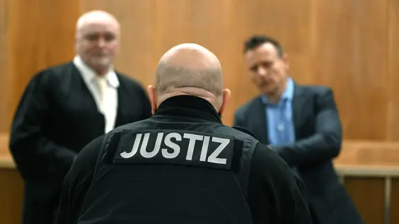 Ein Justizbeamter steht vor der Urteilsverkündung im Gerichtssaal im Landgericht Hannover vor den Anwälten der Angeklagten.