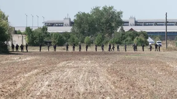 Polizisten in einer Reihe auf einem Feld vor Flughafen 