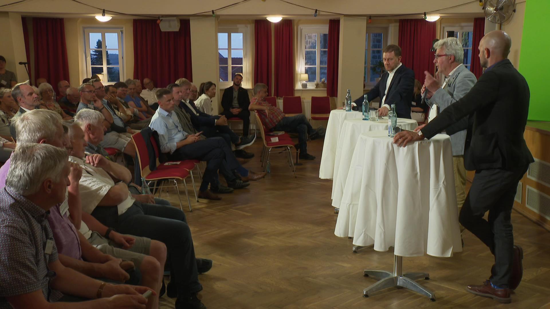 Drei Männer an einem Stehtisch stehen vor Purblikum | MITTELDEUTSCHER RUNDFUNK