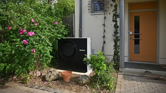 Eine Wärmpepumpe steht in einem Vorgarten eines Doppelhauses.