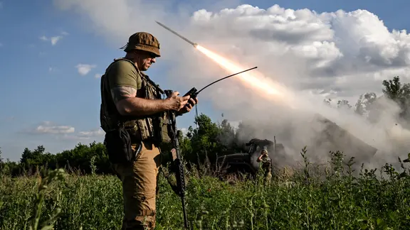 Ukrainischer Soldat mit Fernsteuerung in der Hand, im Hintergrund wird eine Rakete abgefeuert