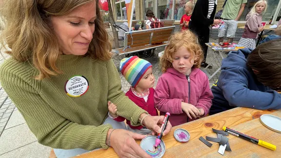 Eine Frau und eine Kinder bemalen Dinge.